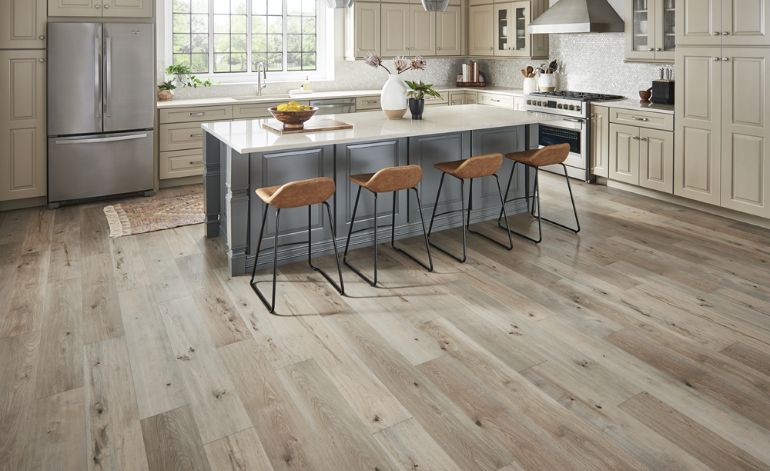 Bright kitchen with wood floors and white cabinets, representing laminate flooring services offered in Sacramento, CA.