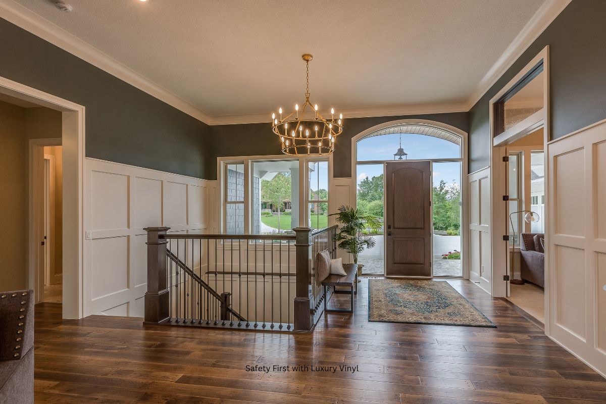 Luxurious entrance hall featuring a chandelier, wooden floors, and large windows with views of the outdoors. Elegant decor and staircase visible.